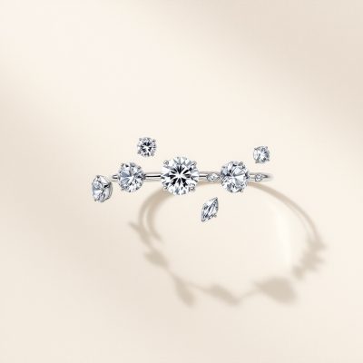 a stage close up photo of a modern minimal jewellery piece made of assymetrically alligned diamonds with an elegant neutral colourbackground