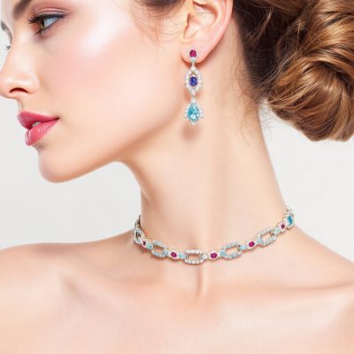 full face of a model wearing 2 modern fancy classy date night jewellery made of colored gemstones